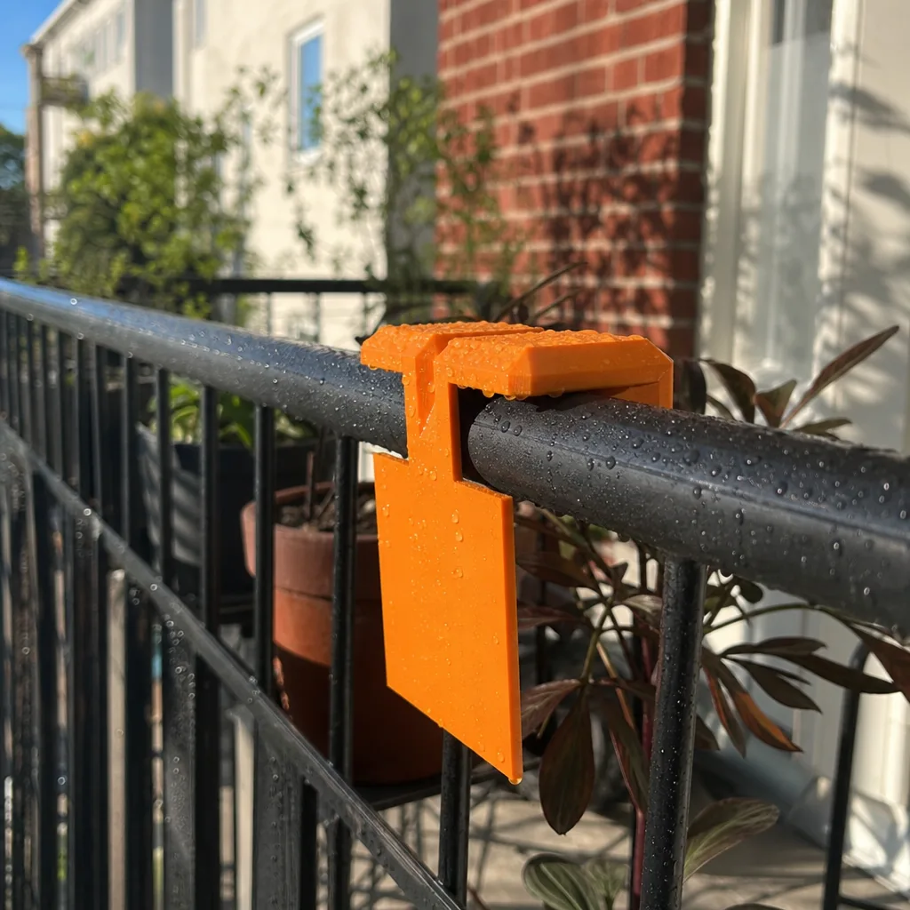 En orange 3D-utskriven hållare monterad utomhus i solljus
